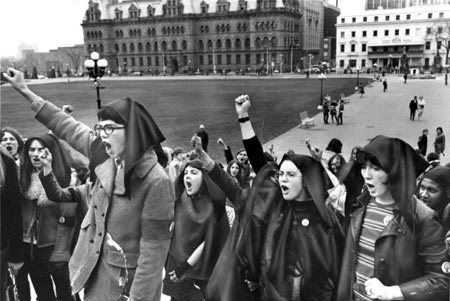un groupe de femmes se tiennent poing levé devant les édifices du Parlement un groupe de femmes se tiennent poing levé devant les édifices du Parlement